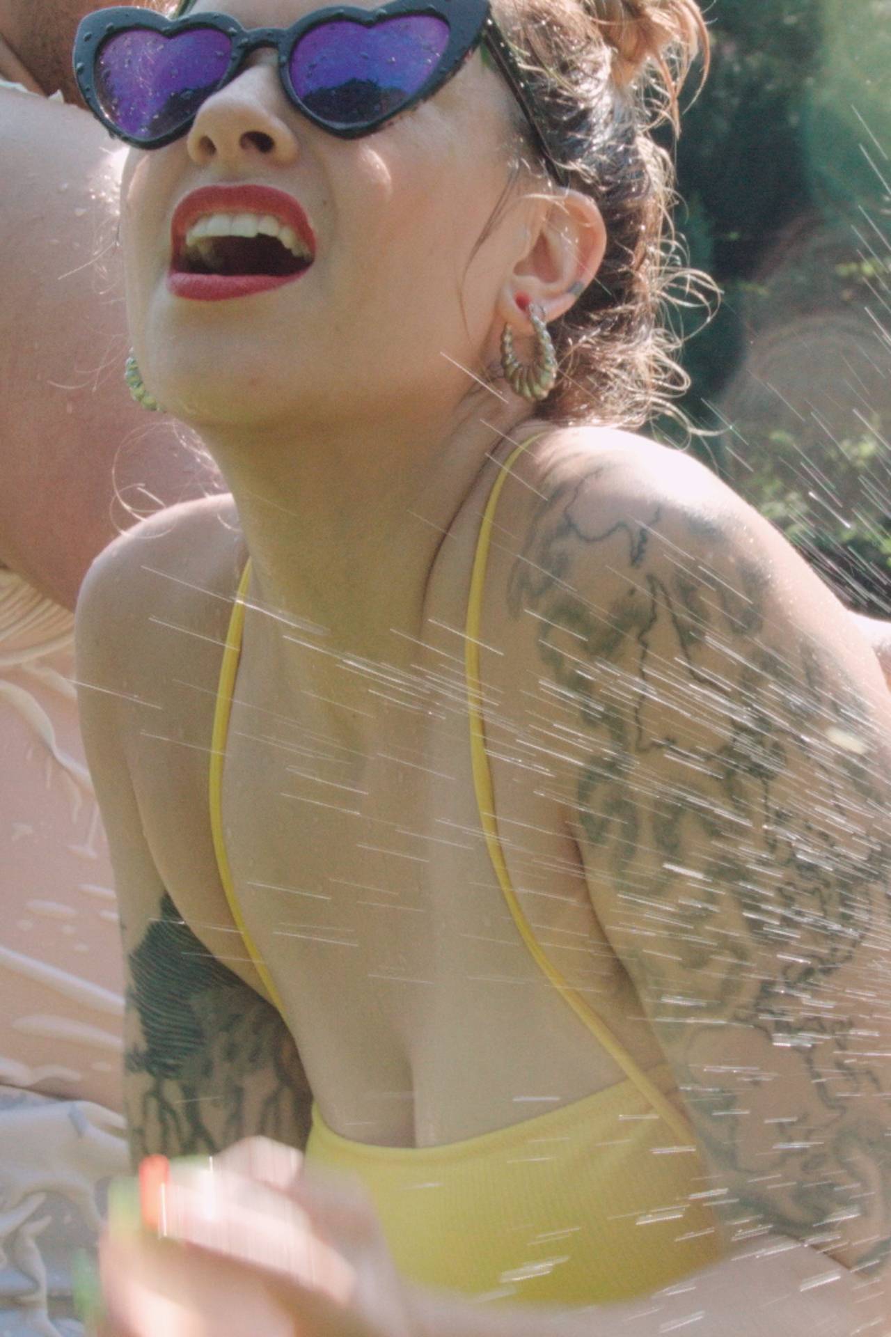 Tattooed porn performer in yellow bikini getting wet in the pool