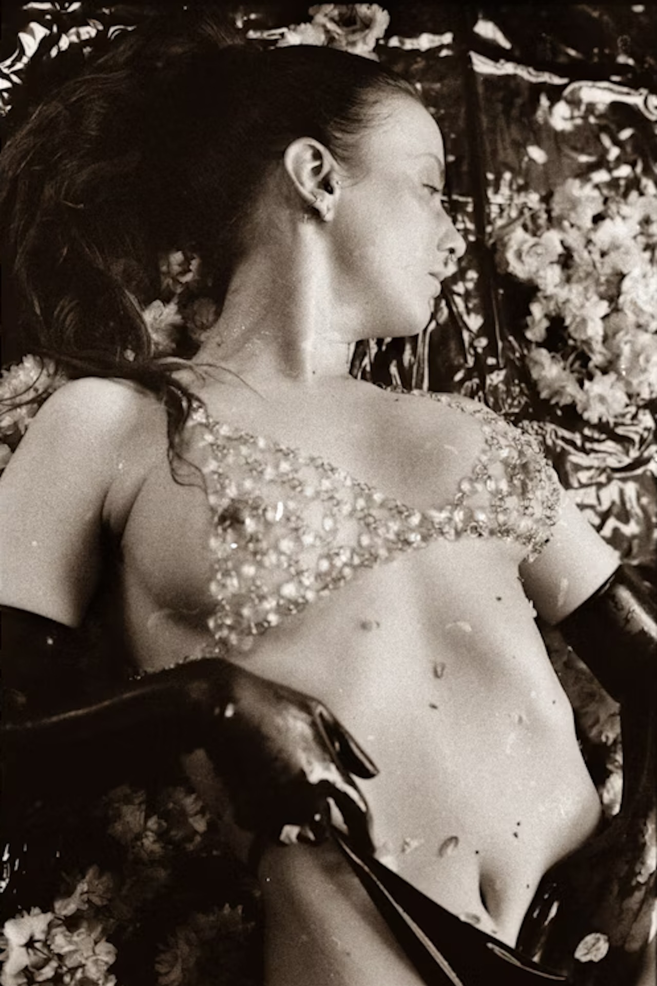 Fourchambers petals Vex Ashley Schwarzweiß-Foto von Vex in einem Glasperlen-BH und Latexhandschuhen.